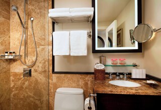 A bathroom with a shower, toilet, sink, and a mirror.