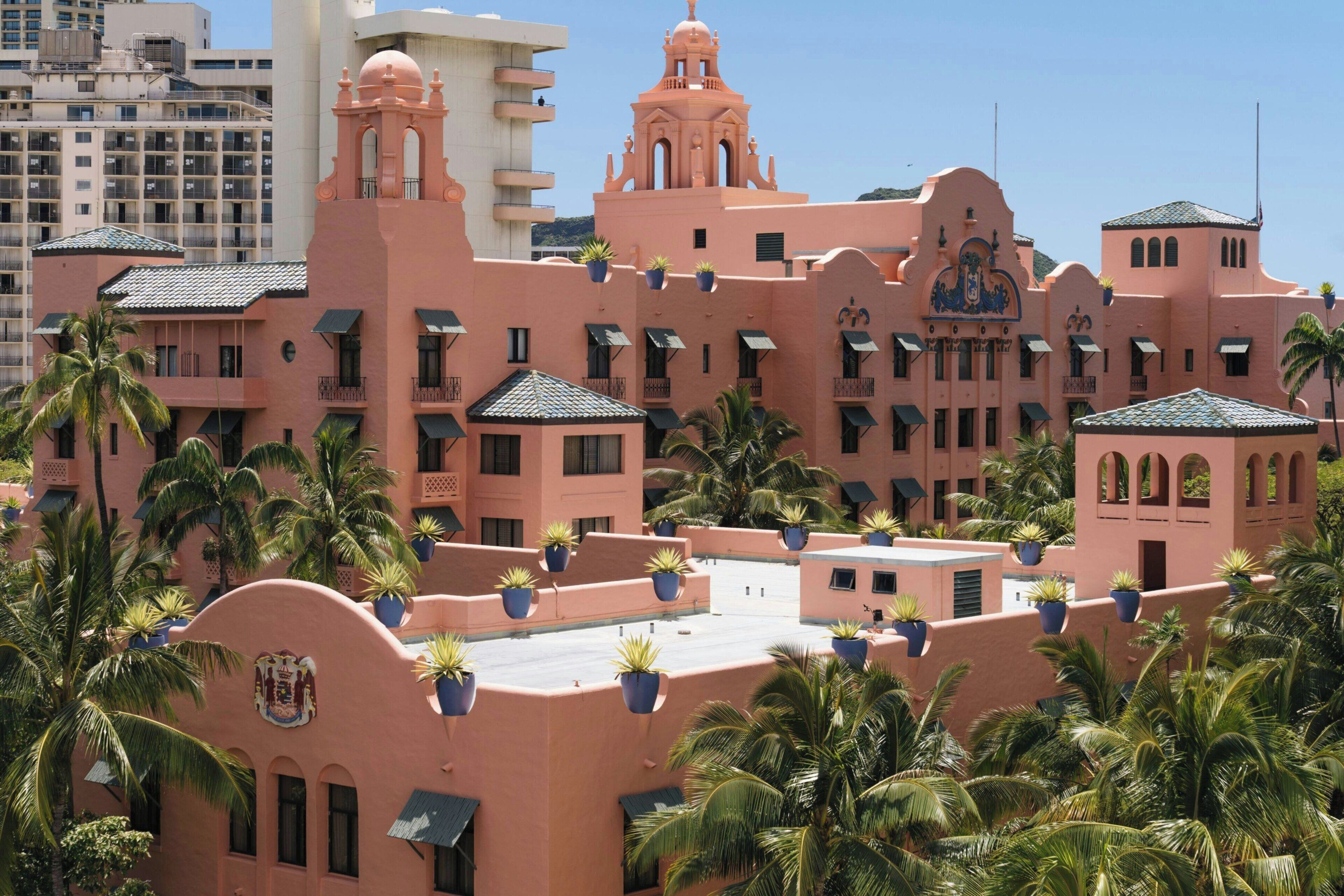 A pink building with multiple balconies and potted plants.