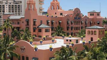 A pink building with multiple balconies and potted plants.