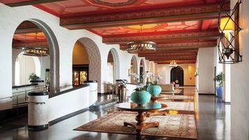 Un'ampia hall con un imponente lampadario, colonne ad arco e un tavolo rotondo centrale con vasi decorativi.
