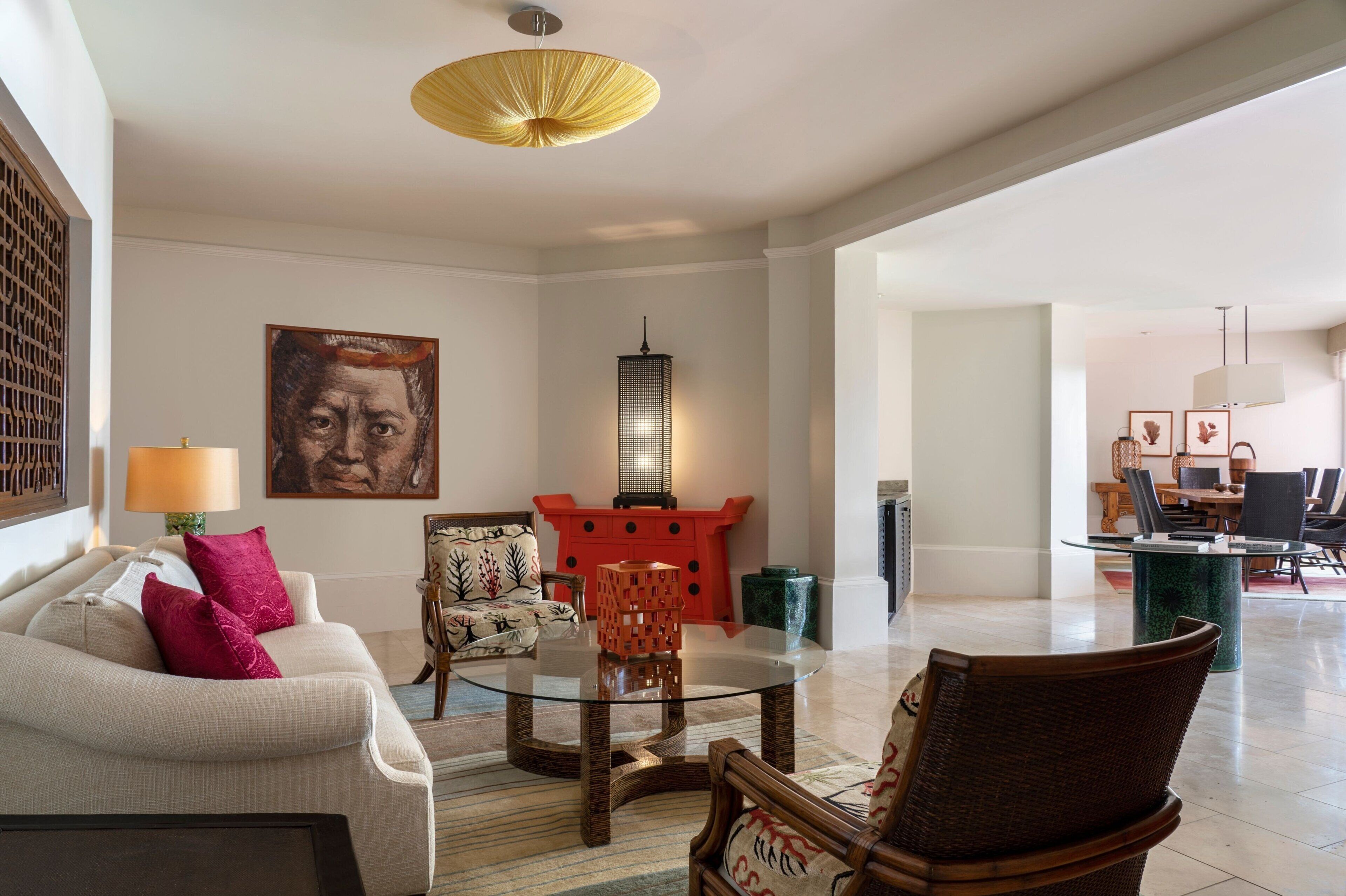 A spacious living room with a beige sofa, a glass coffee table, and a red accent wall.