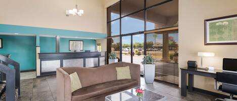 A modern lobby with a sofa, coffee table, and a reception desk.