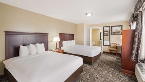 A hotel room with two beds, a desk, a chair, a mirror, and a door leading to another room. - Best Western Conway (Conway)