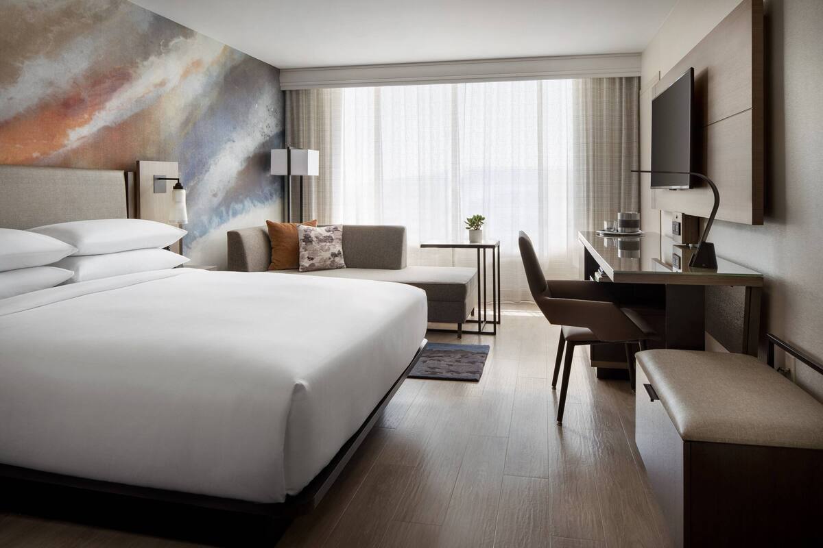 Una habitación de hotel moderna con una cama grande, un escritorio y una televisión.