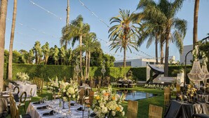 An outdoor dining area with tables set for a meal, surrounded by palm trees and a pool. - Torrance Marriott Redondo Beach (Torrance)