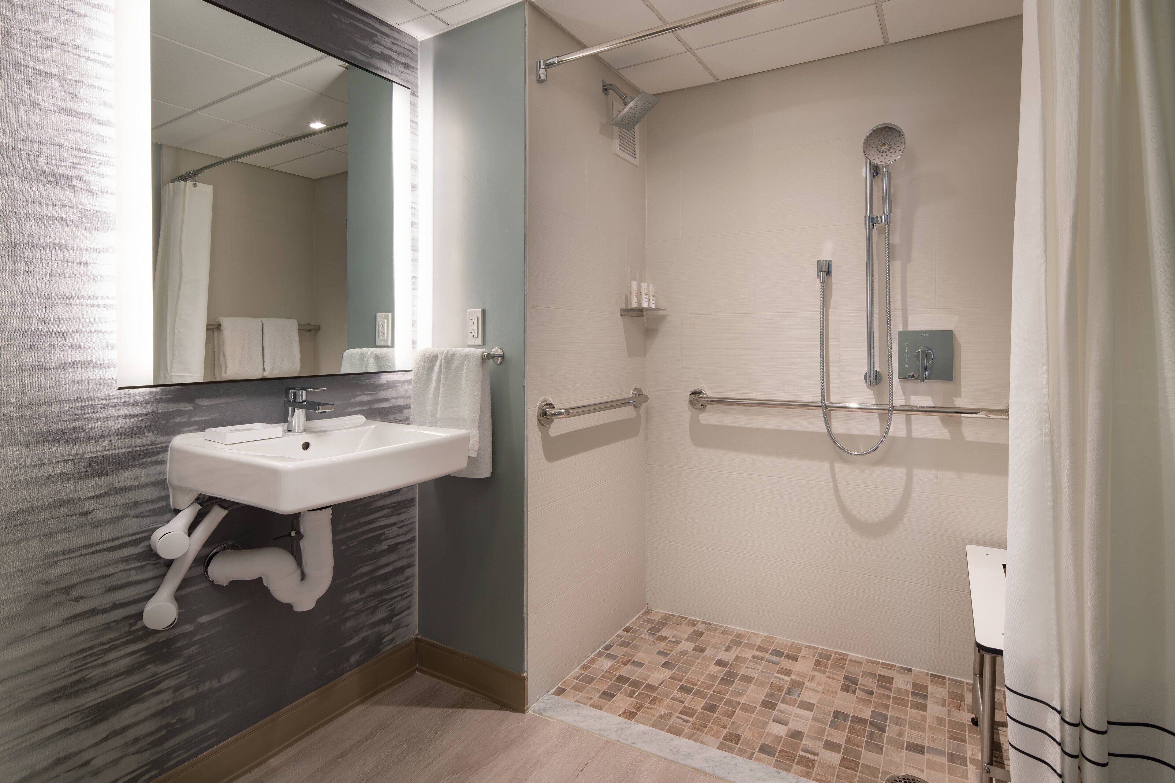 Un bagno moderno con doccia, lavandino e specchio.