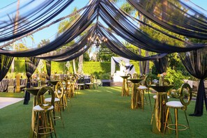 An outdoor event space with tables and chairs, draped with fabric, and surrounded by greenery. - Torrance Marriott Redondo Beach (Torrance)