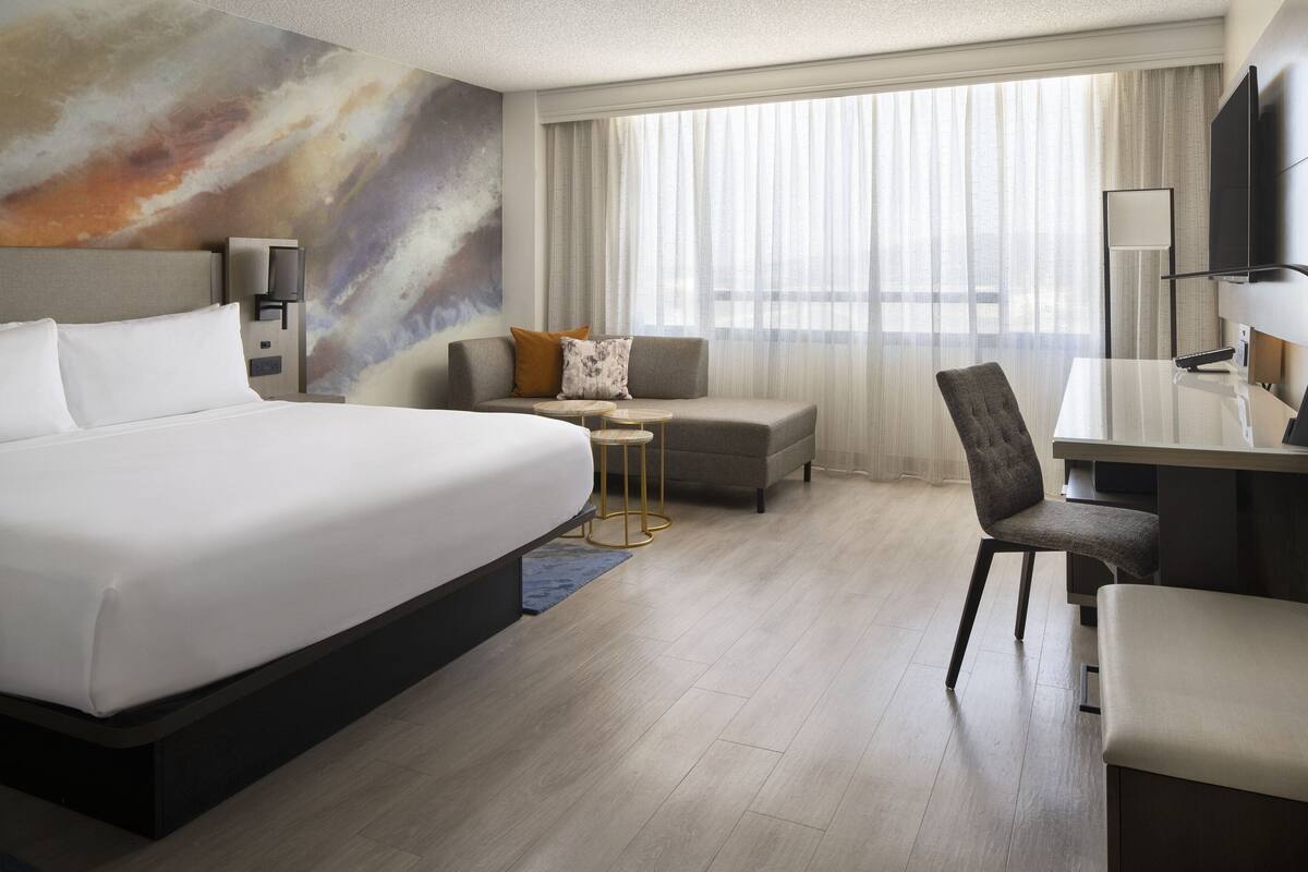 Una habitación de hotel moderna con una cama grande, un sofá, un escritorio y una televisión.