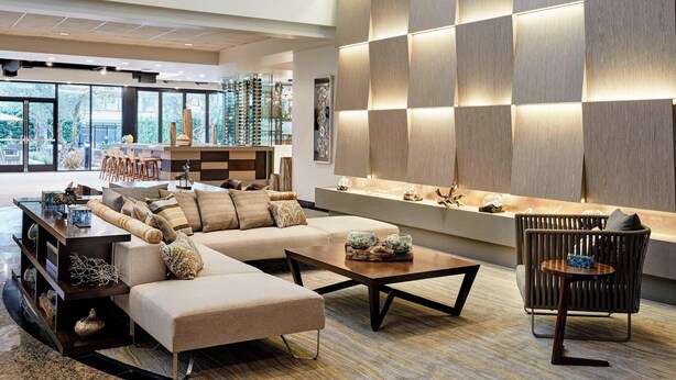 A modern living room with a sectional sofa, a coffee table, and a chair. There is a large window providing a view of the outdoors. - Torrance Marriott Redondo Beach (Torrance)