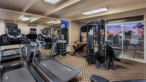 A gym with treadmills, weight machines, and a large window with a view of the sunset. - Kayenta Monument Valley Inn (Kayenta)
