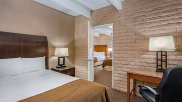 A hotel room with a bed, bedside table, lamp, desk, and chair.