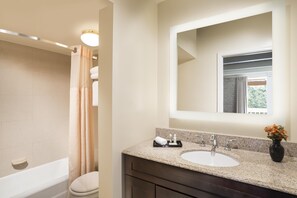 A bathroom with a bathtub, toilet, sink, and a mirror above the sink.