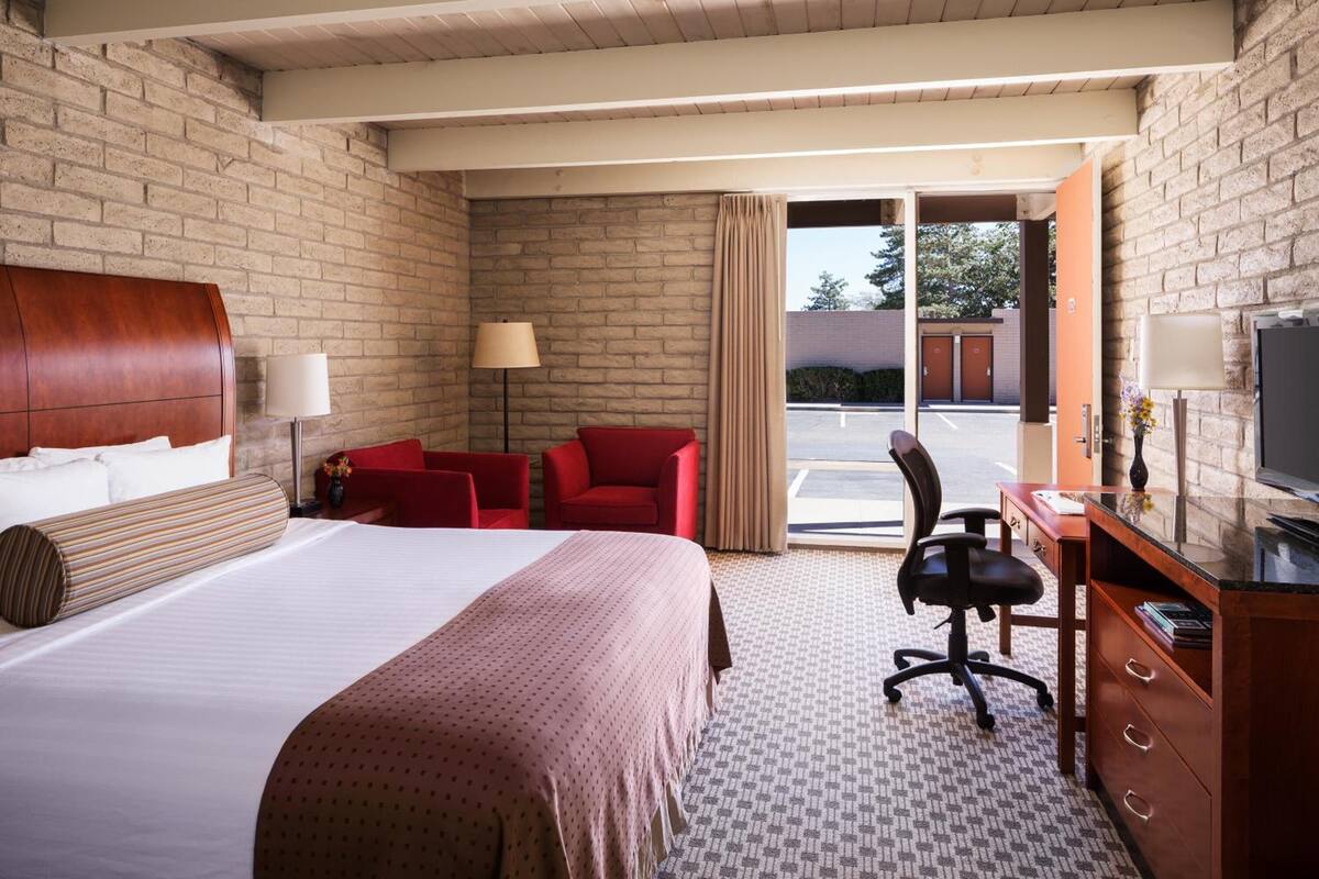 Une chambre d’hôtel avec un grand lit, un bureau avec un ordinateur, une chaise et un téléviseur.