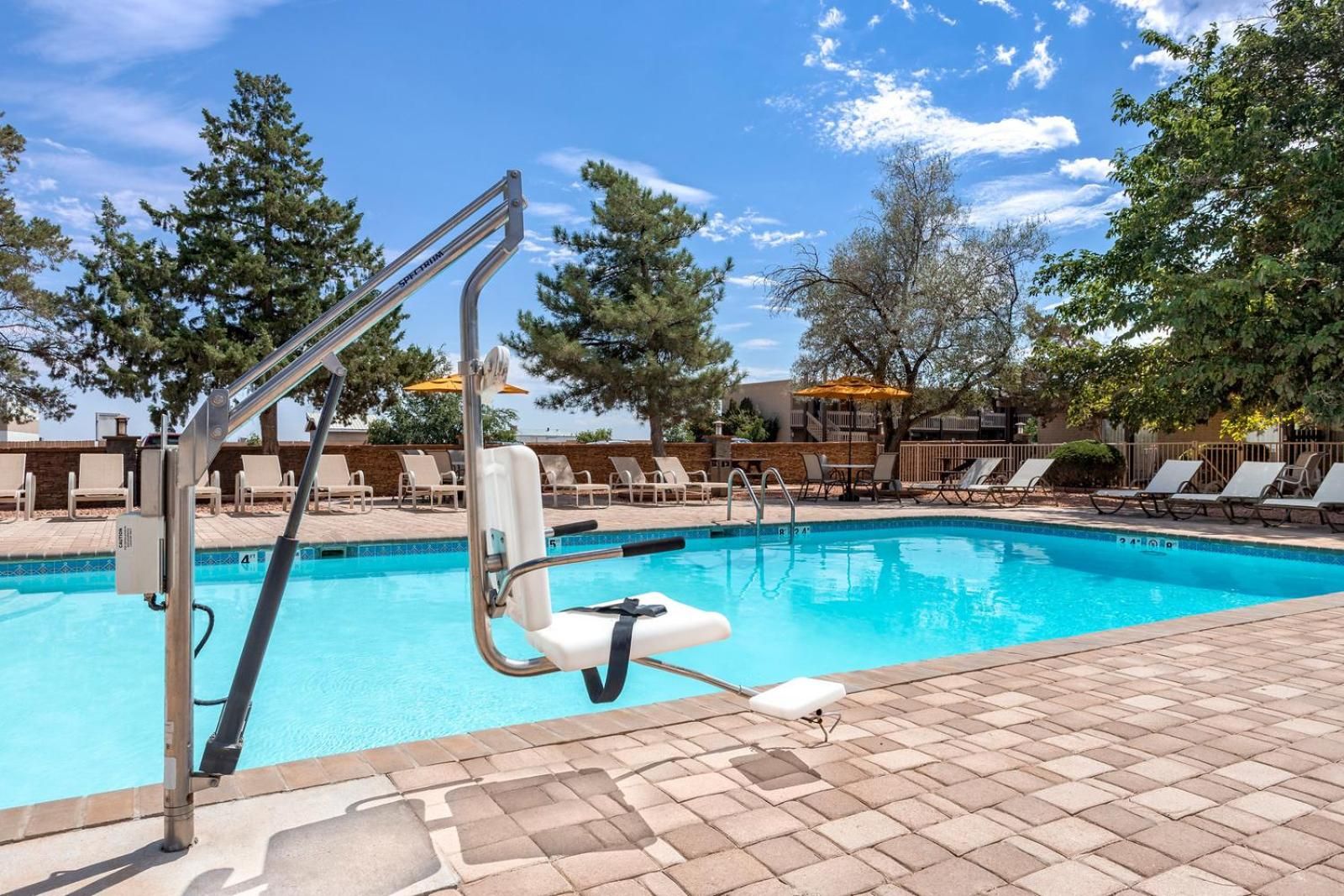 A swimming pool with a pool ladder, lounge chairs, and a tiled deck.