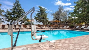 A swimming pool with a pool ladder, lounge chairs, and a tiled deck.