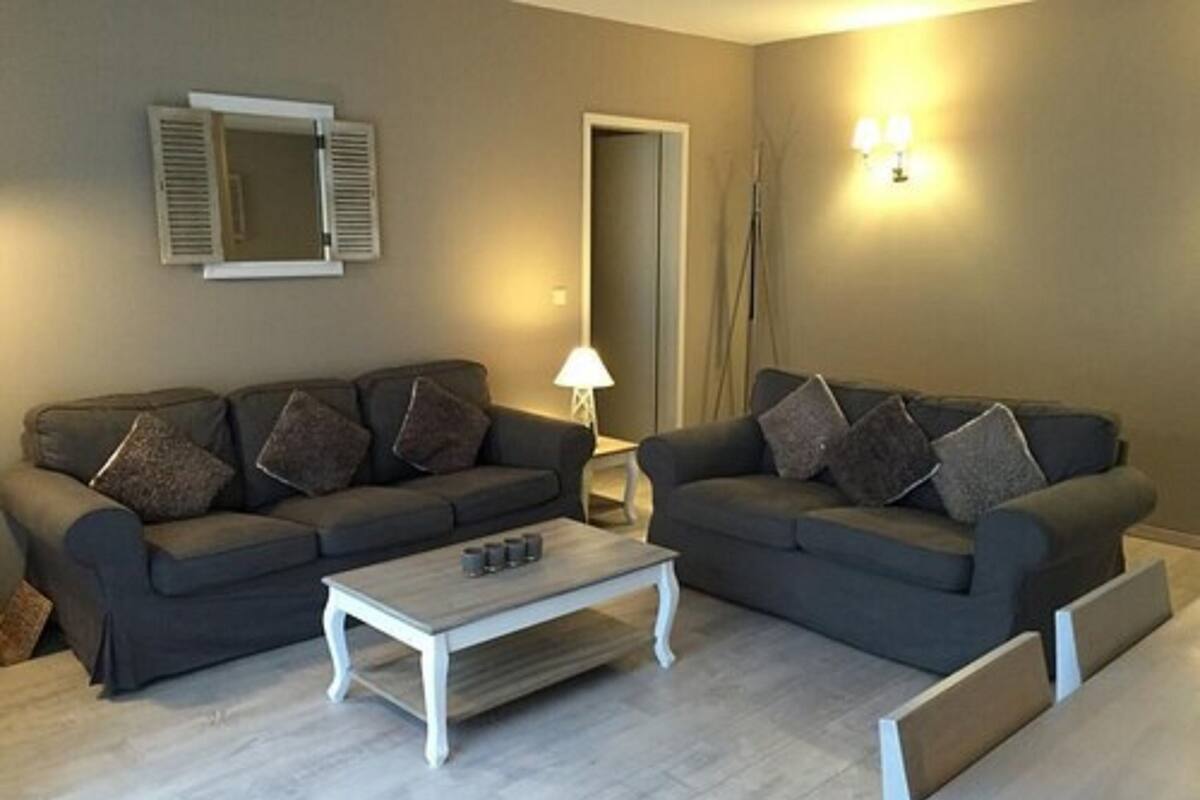 A living room with two dark grey sofas, a white coffee table, and a lamp.