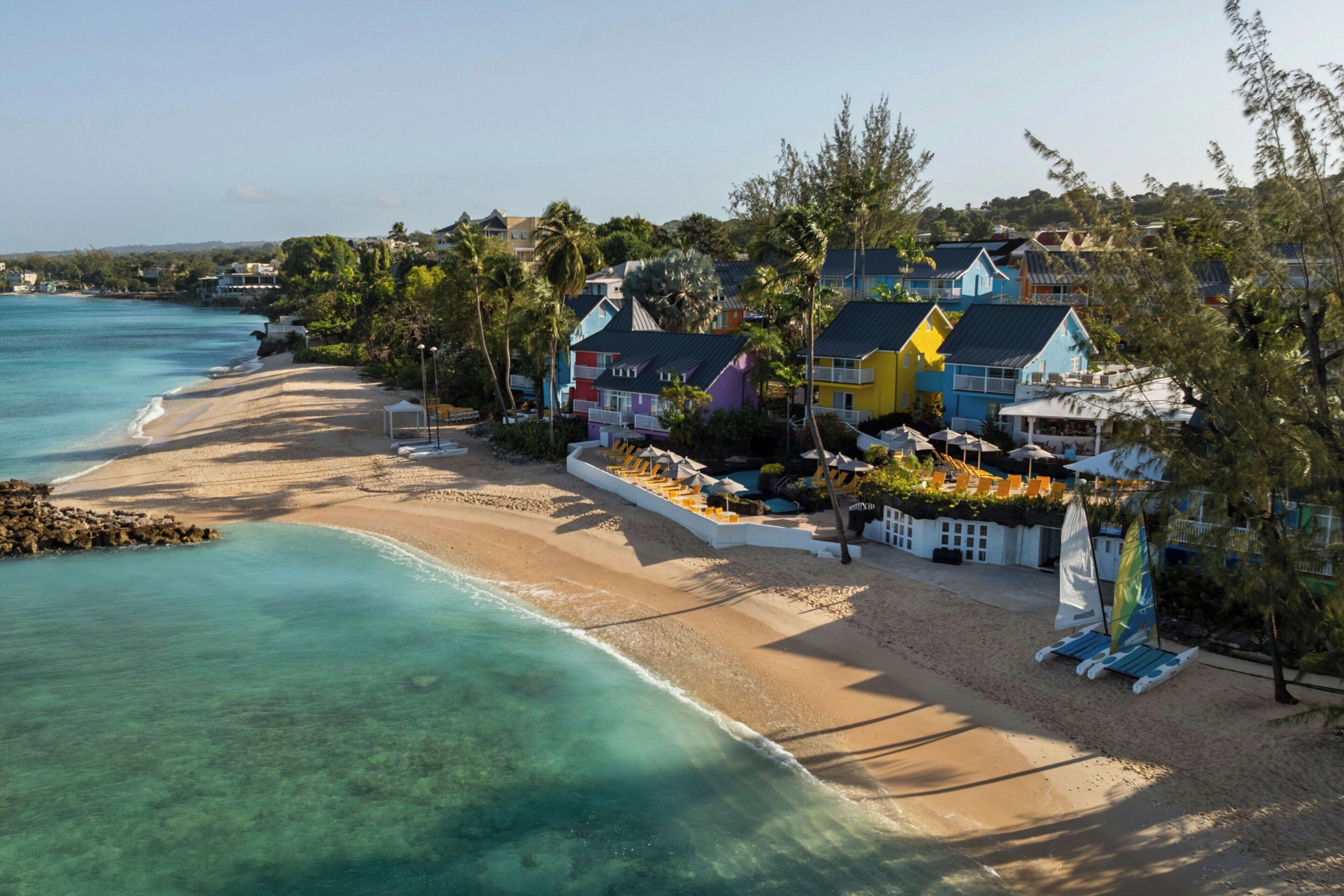 A beachfront property with colorful houses, a sandy beach, and clear turquoise waters.