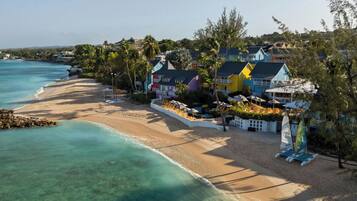 A beachfront property with colorful houses, a sandy beach, and clear turquoise waters.