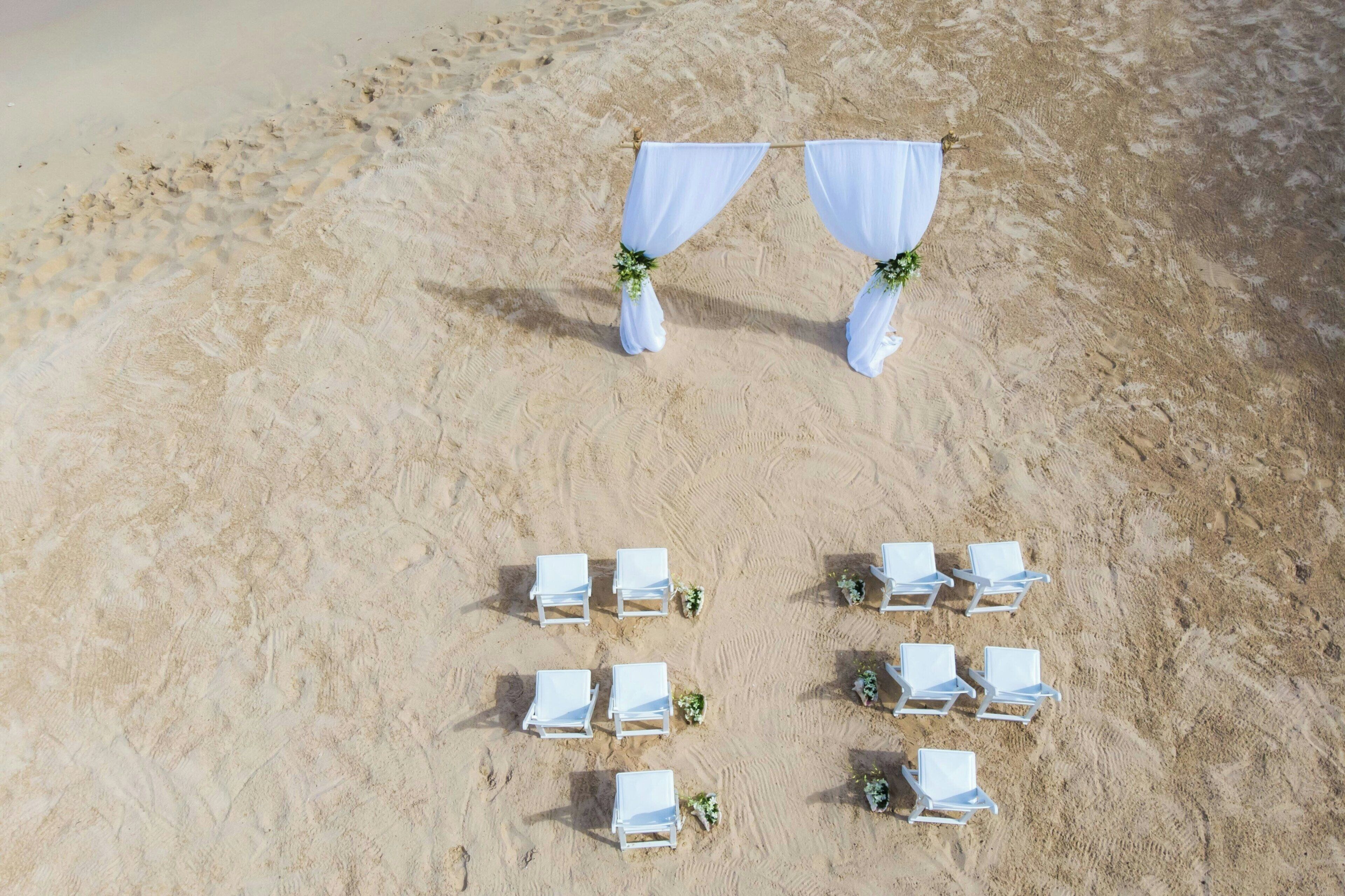 Decoración para una boda en la playa, con sillas y cortinas blancas.