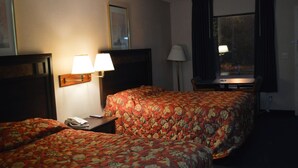 Une chambre d’hôtel avec deux lits, un bureau avec une lampe, un téléphone et une fenêtre avec des rideaux.