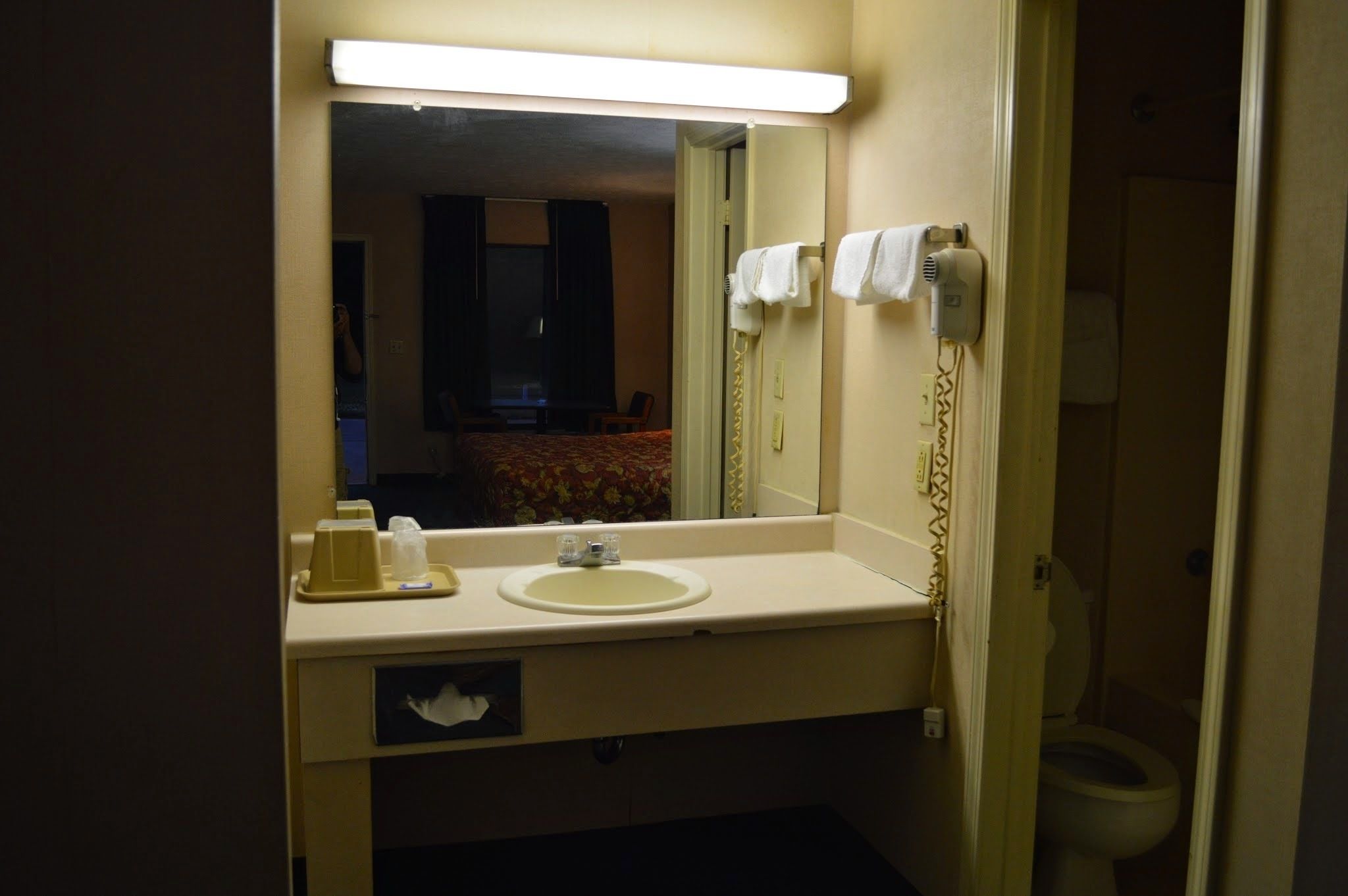 A hotel bathroom with a sink, mirror, and towel rack.