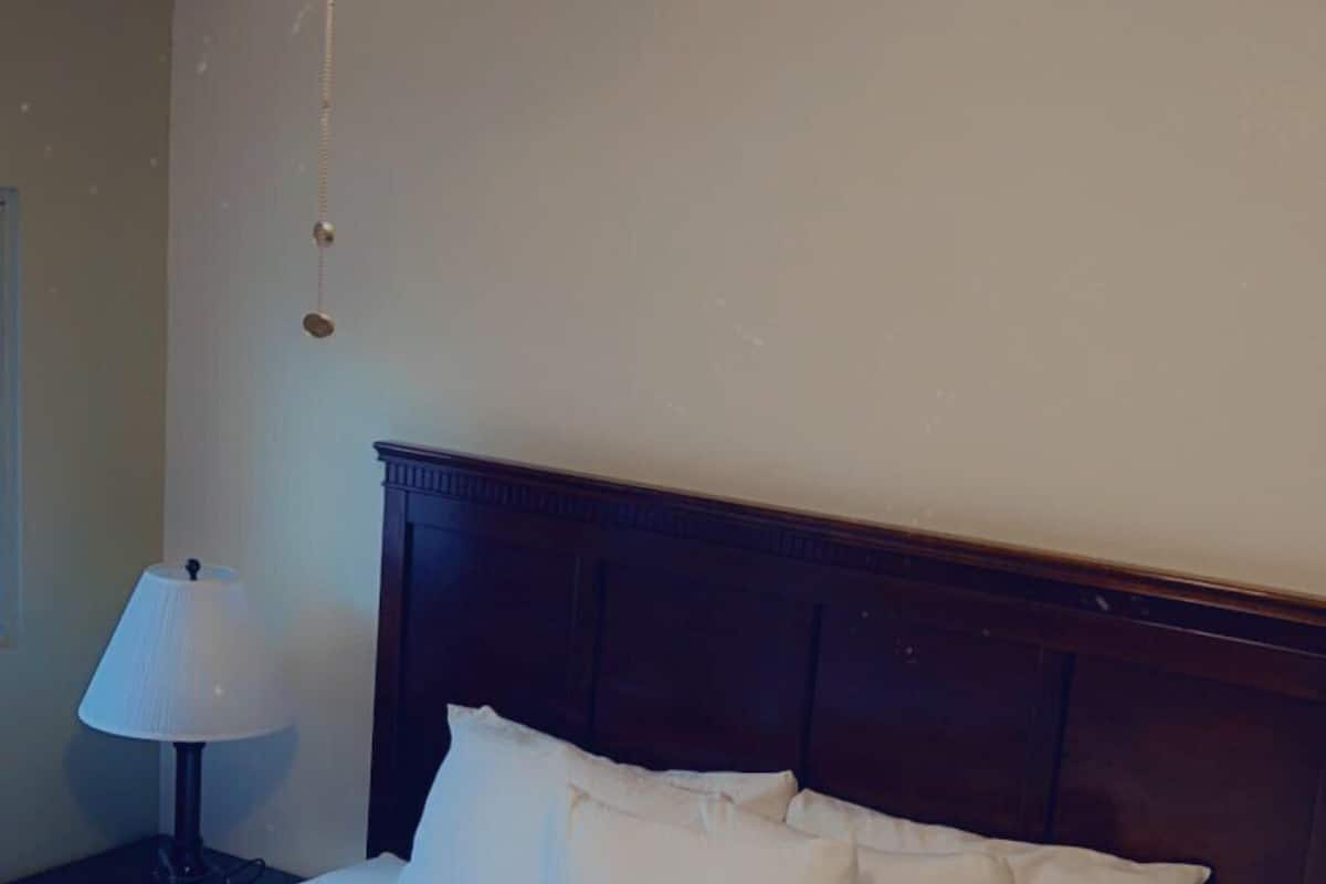 A bedroom with a bed, a nightstand, a lamp, and a ceiling fan.