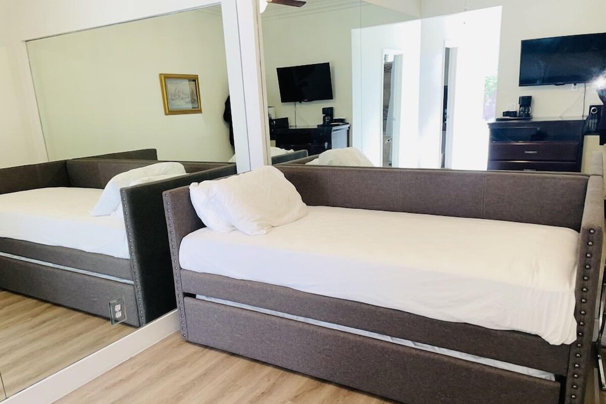 A room with two beds, a TV, and a desk with a computer.