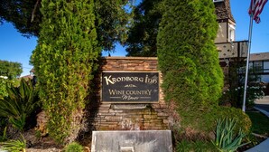 A sign for Kronborg Inn Wine Country Manor with a stone wall and a water feature. - Kronborg Inn (Solvang)