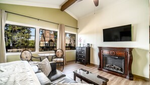 A room with a bed, a sofa, a fireplace, a television, and a dining area with a table and chairs. - Kronborg Inn (Solvang)