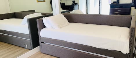 A room with two beds, a large mirror, a TV, and a coffee maker.