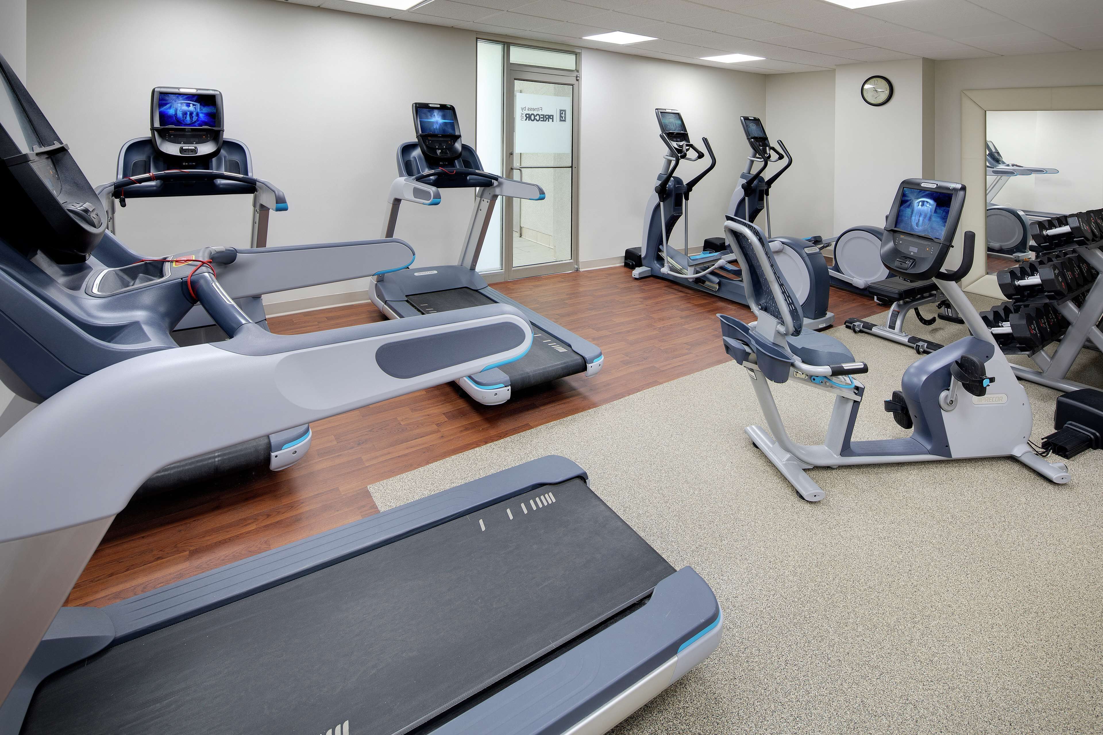 Un gimnasio con cintas de correr, elípticas y una bicicleta estática.