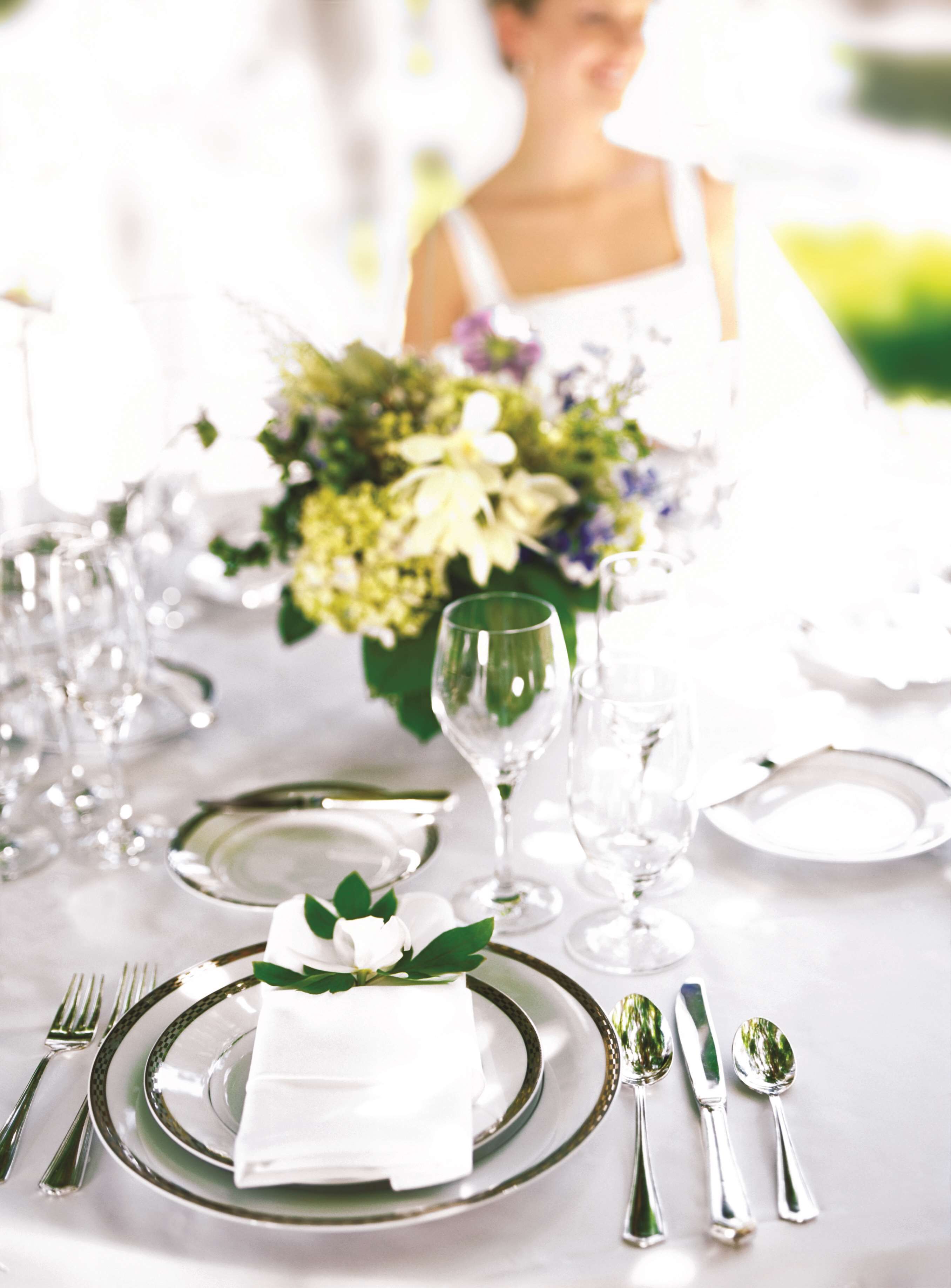 A table set for a formal event with a centerpiece of flowers, clear glassware, and silverware.