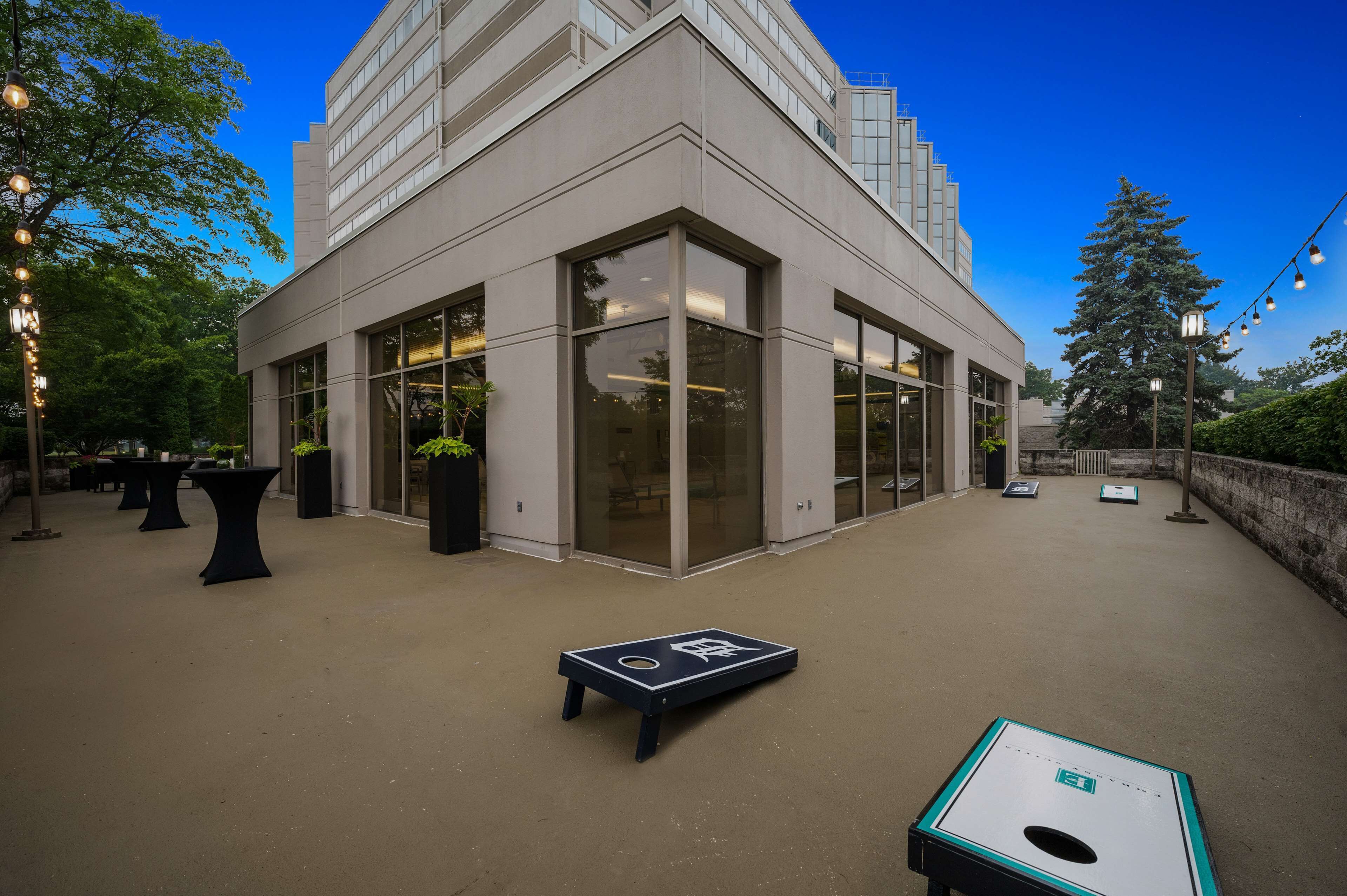 A modern building with large windows and a courtyard with tables and a game table.