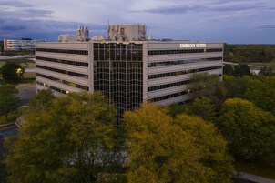 Un edificio moderno con el letrero "Embassy Suites" en la parte superior. Tiene varios pisos con ventanas amplias y está rodeado de árboles.