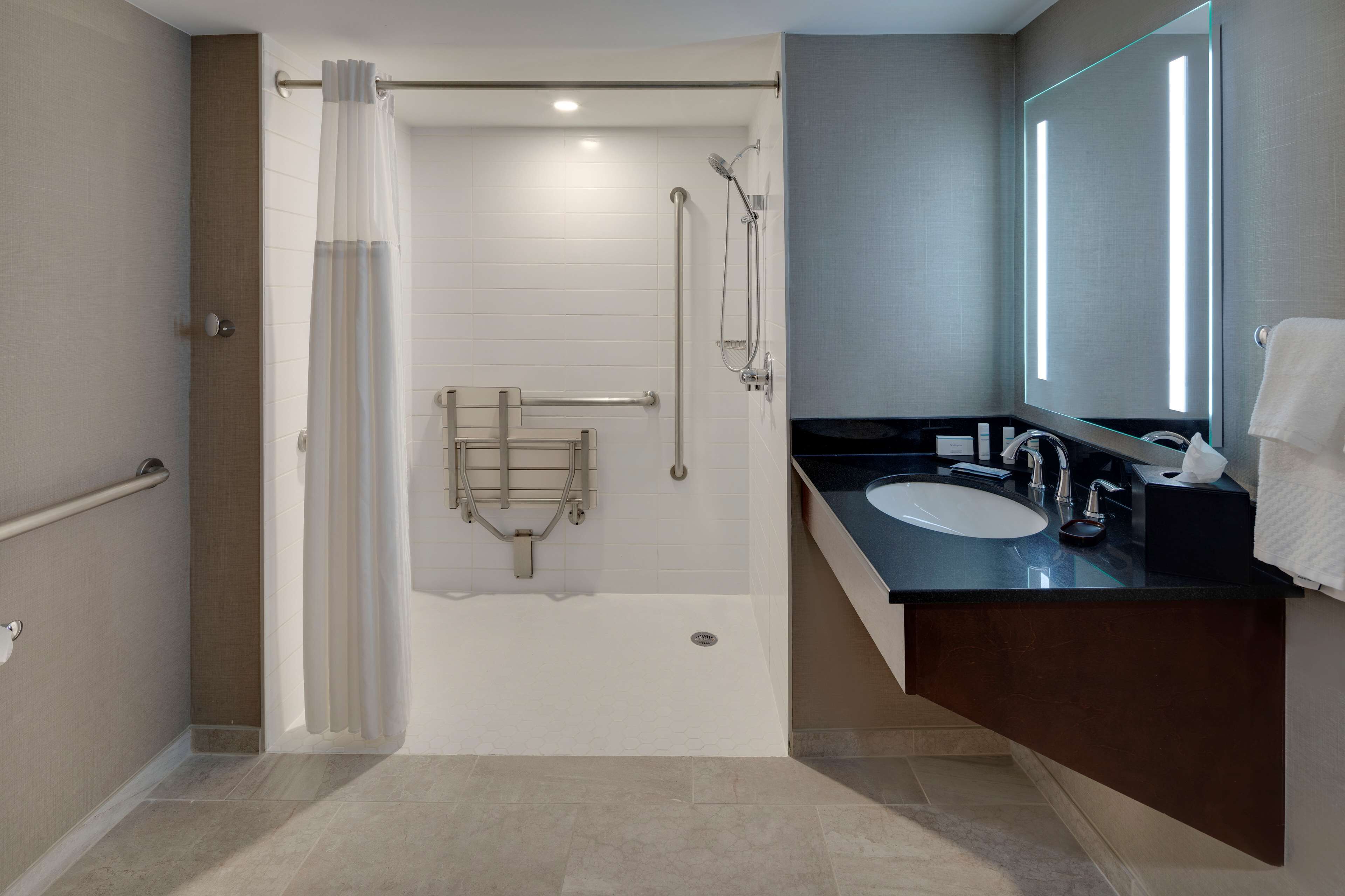 Un baño moderno con ducha, inodoro con cerramiento de vidrio y tocador con espejo.