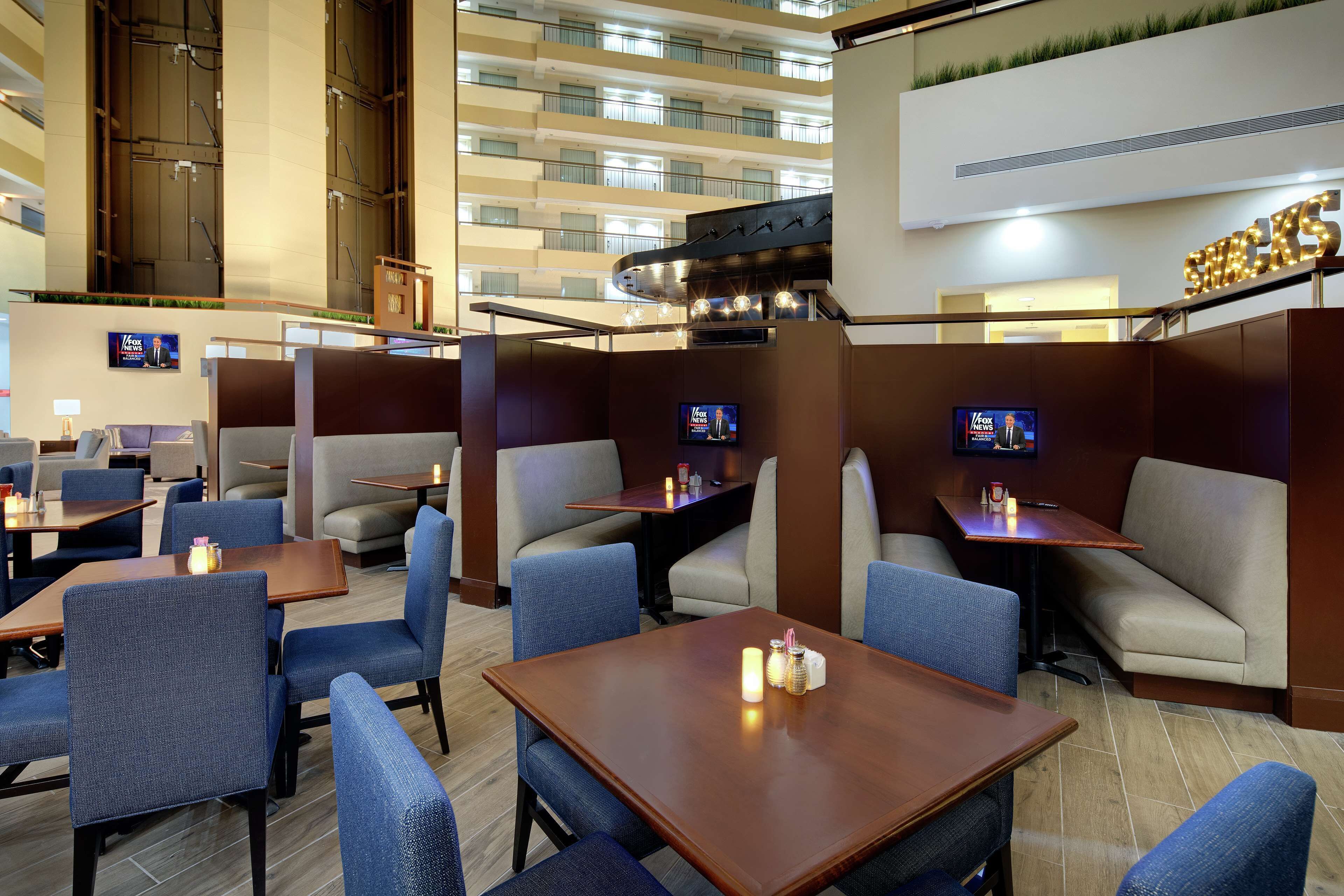 A hotel lobby with multiple seating areas, including tables and booths, and a large kitchen area with a sign reading "SHACKS".