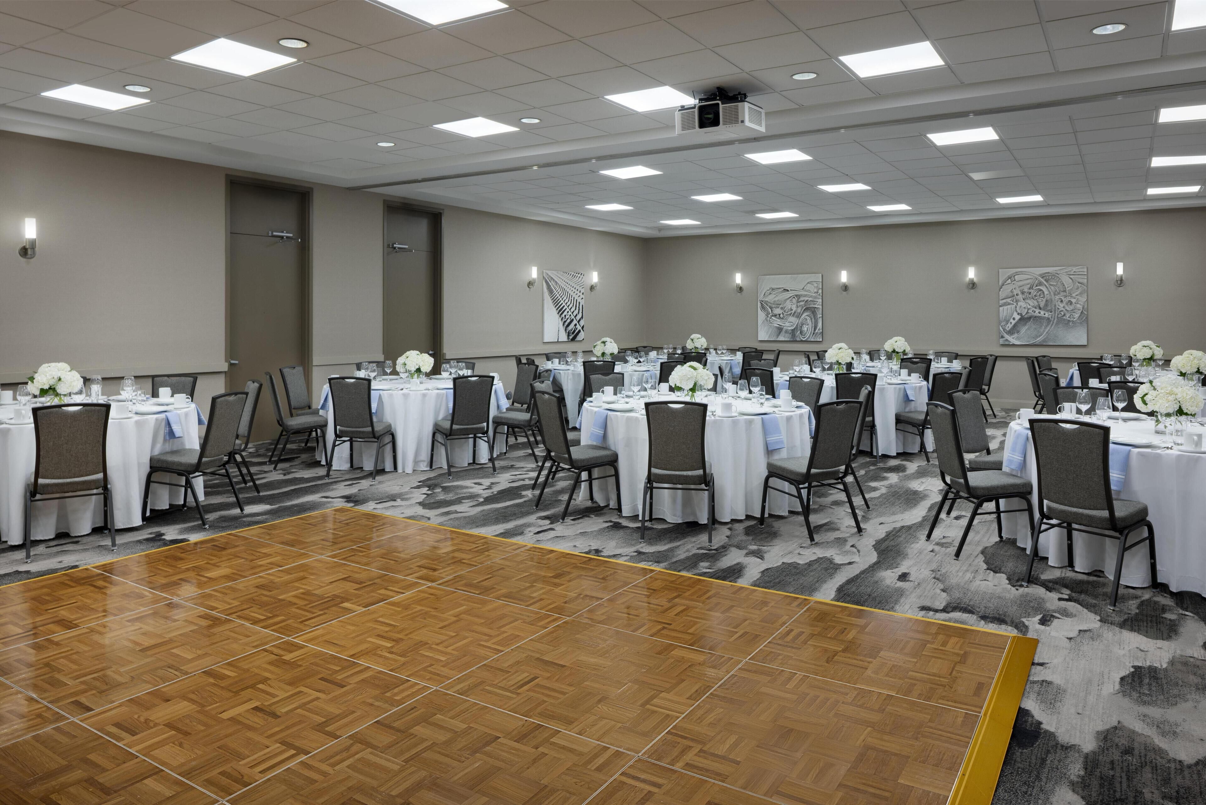 Un salón de conferencias con varias mesas, sillas y una pista de baile.