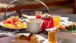 A breakfast setting with a plate of fruit, a teapot, a cup, and a glass of orange juice. - Novotel Nice Centre Vieux Nice (Nice)