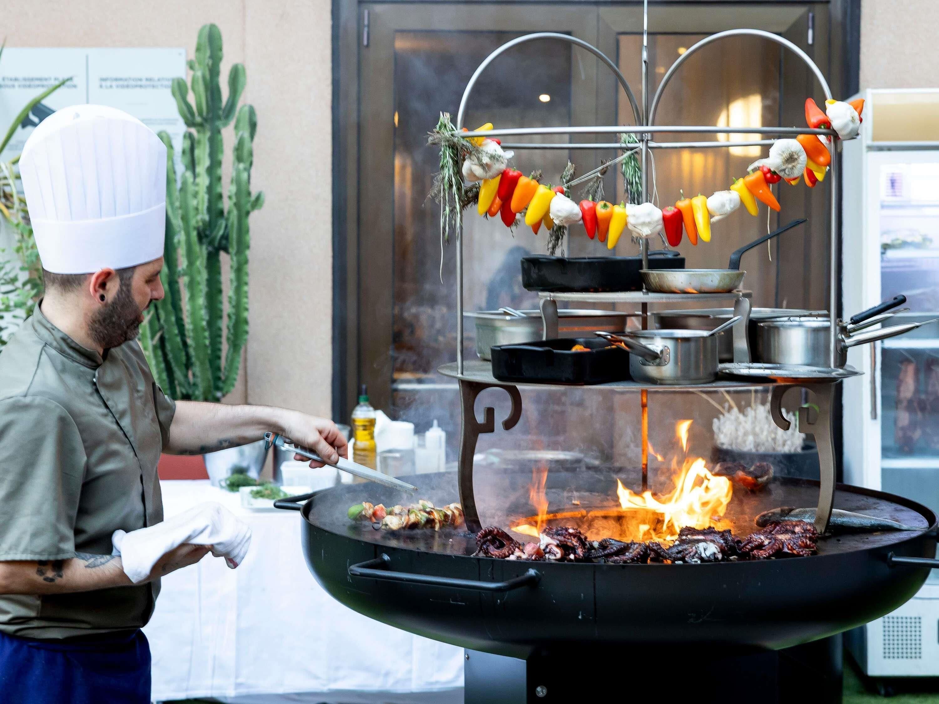 A chef grilling octopus on an outdoor grill with a fire underneath.