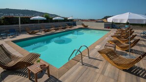 A pool area with wooden loungers, umbrellas, and a clear view of the city in the background. - Novotel Nice Centre Vieux Nice (Nice)