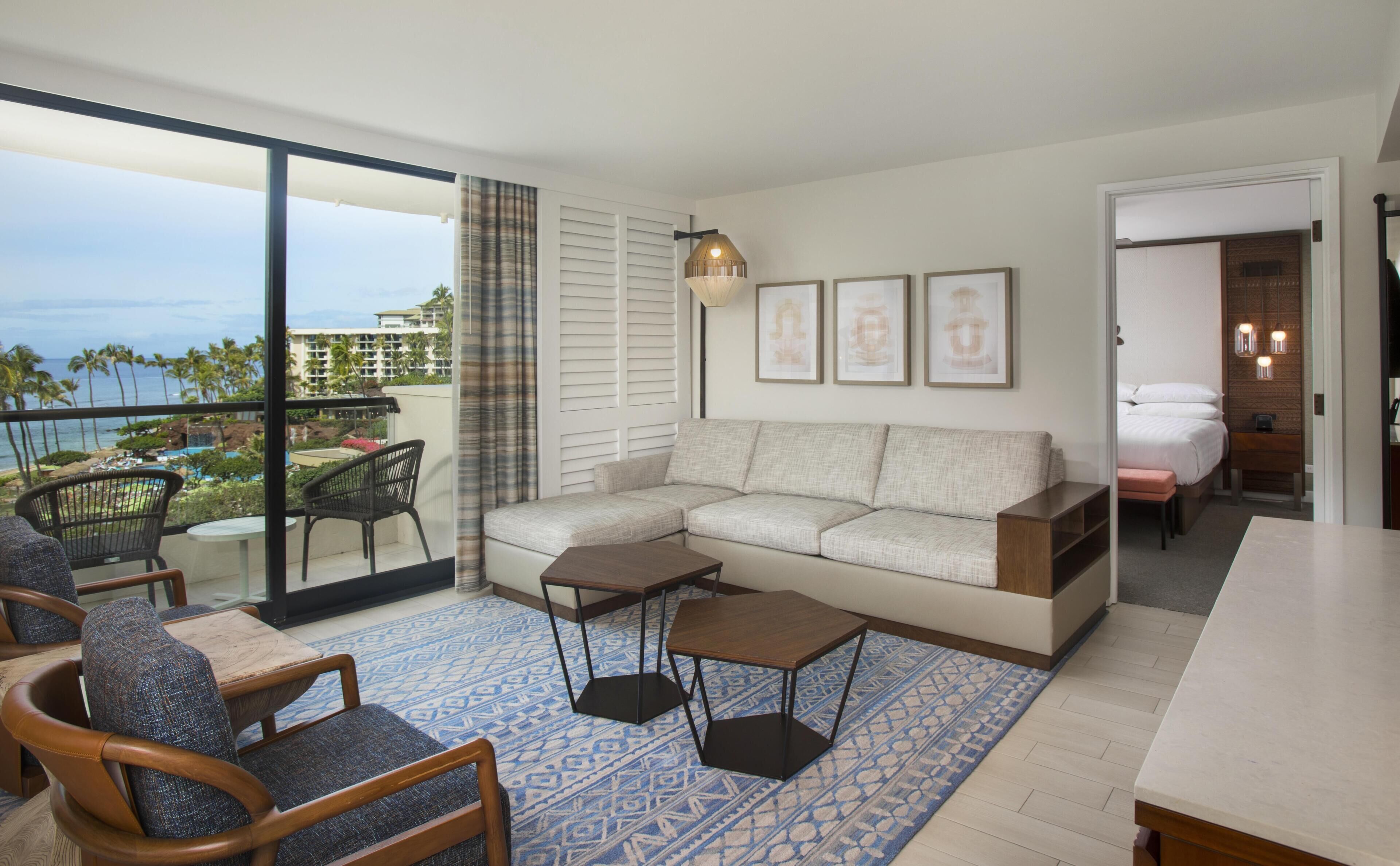 A modern living room with a sofa, chairs, a coffee table, and a view of the ocean.