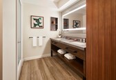 A modern bathroom with a wooden vanity, two sinks, and a large mirror.