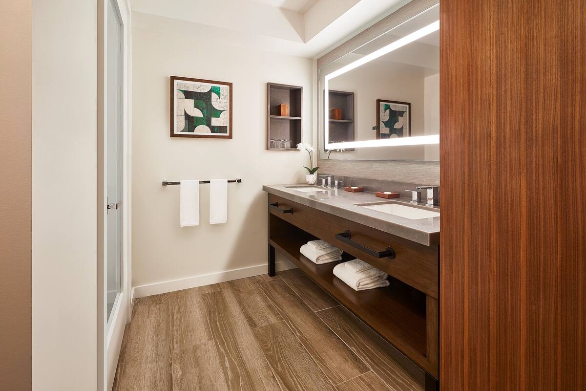 A modern bathroom with a wooden vanity, two sinks, and a large mirror.