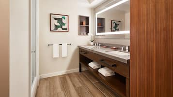 Un baño moderno con tocador de madera, dos lavamanos y un espejo grande.