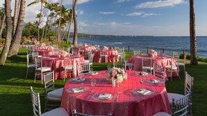 An outdoor dining area with tables set for a meal, overlooking a body of water.