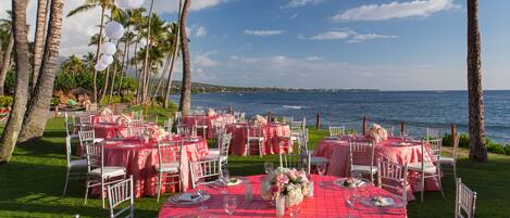 An outdoor dining area with tables set for a meal, overlooking a body of water.