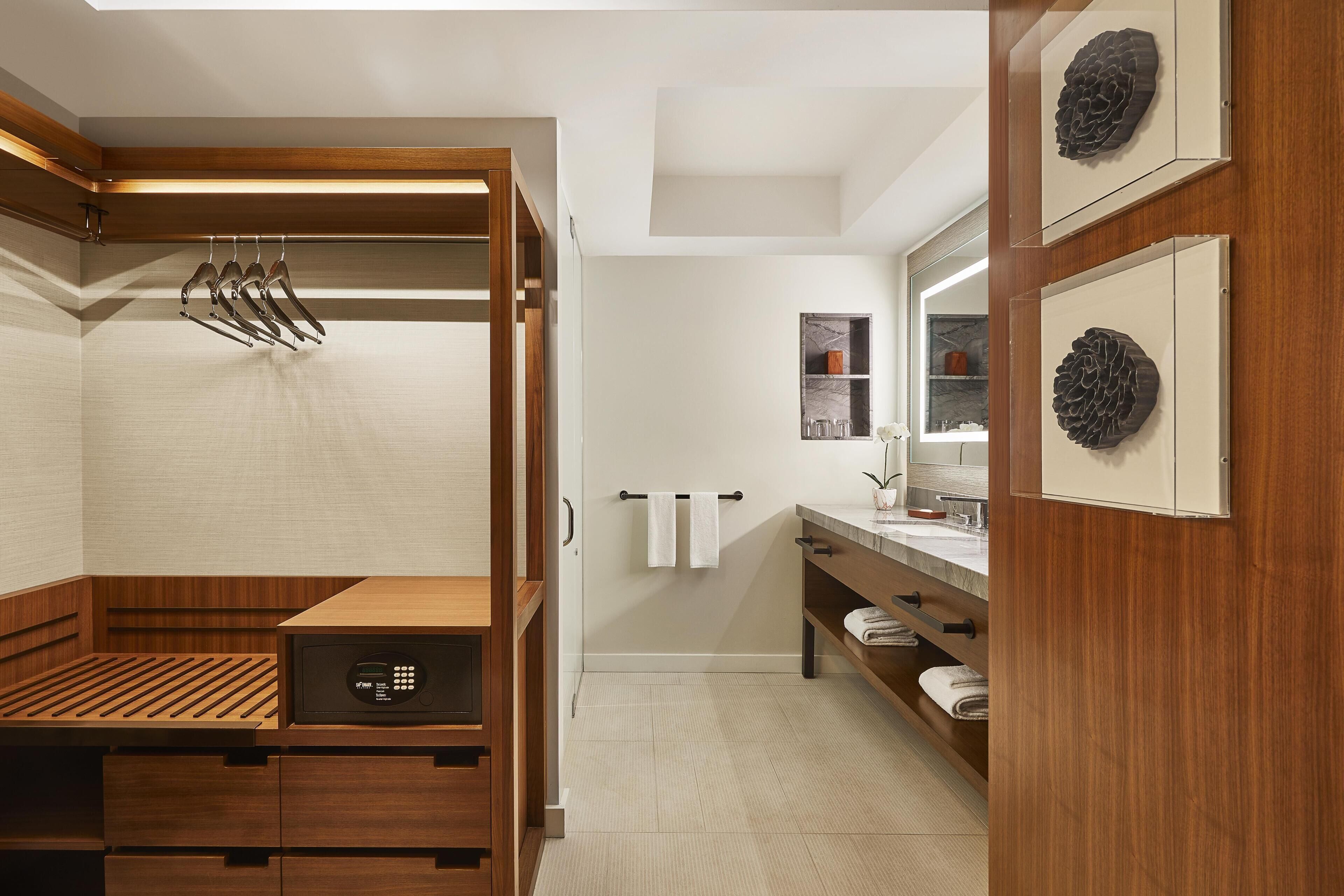 Un baño moderno con tocador de madera, calefacción integrada y un espejo con una piña decorativa.