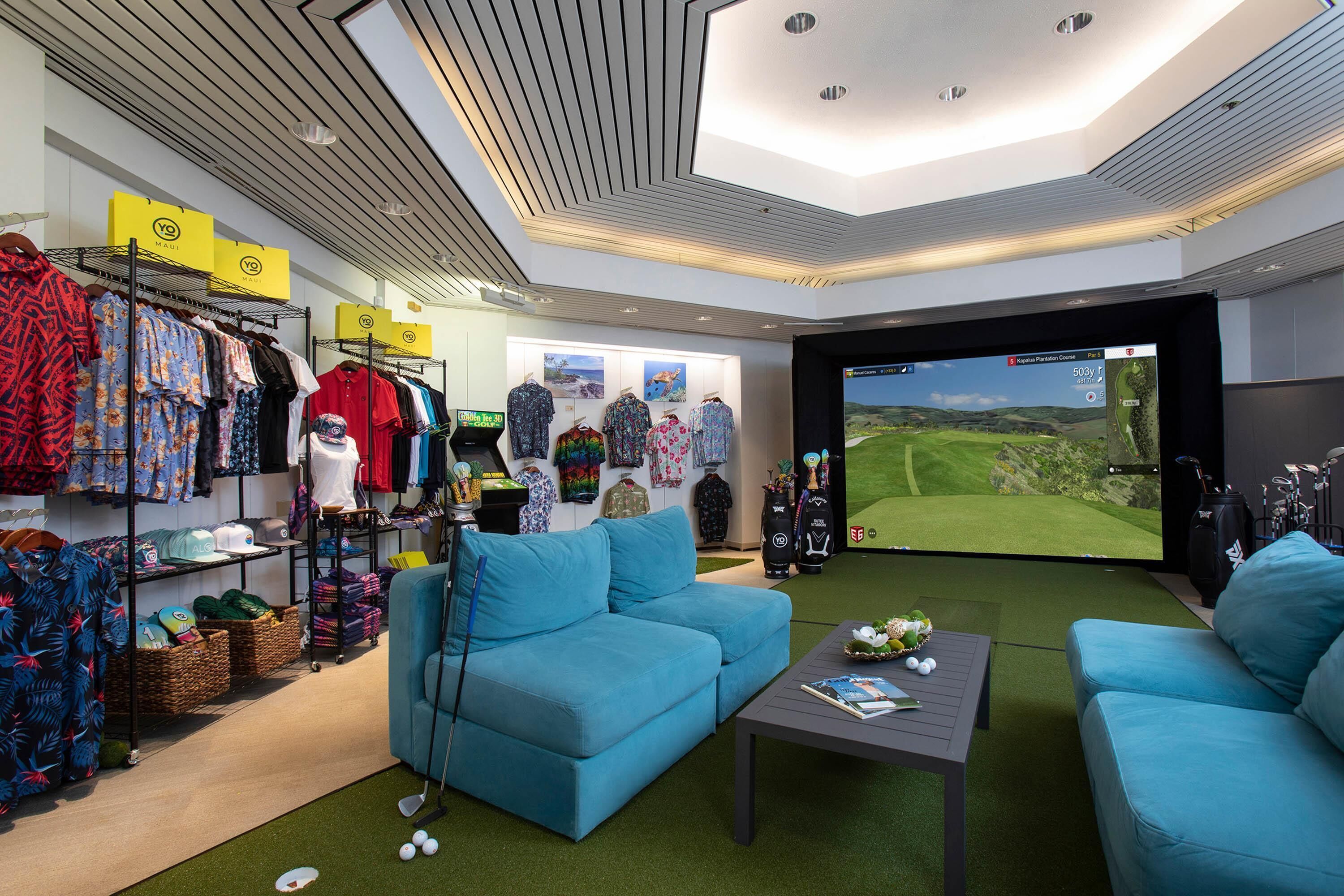 Una habitación con decoración temática de golf, incluyendo un carrito de golf, botes de golf y una pantalla grande que muestra vistas de un campo de golf.