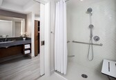 A modern bathroom with a shower, a vanity with a mirror, and a towel rack.