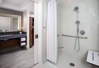 A modern bathroom with a shower, a vanity with a mirror, and a towel rack.